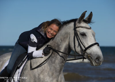 Pferd und Reiterin glücklich am Meer.